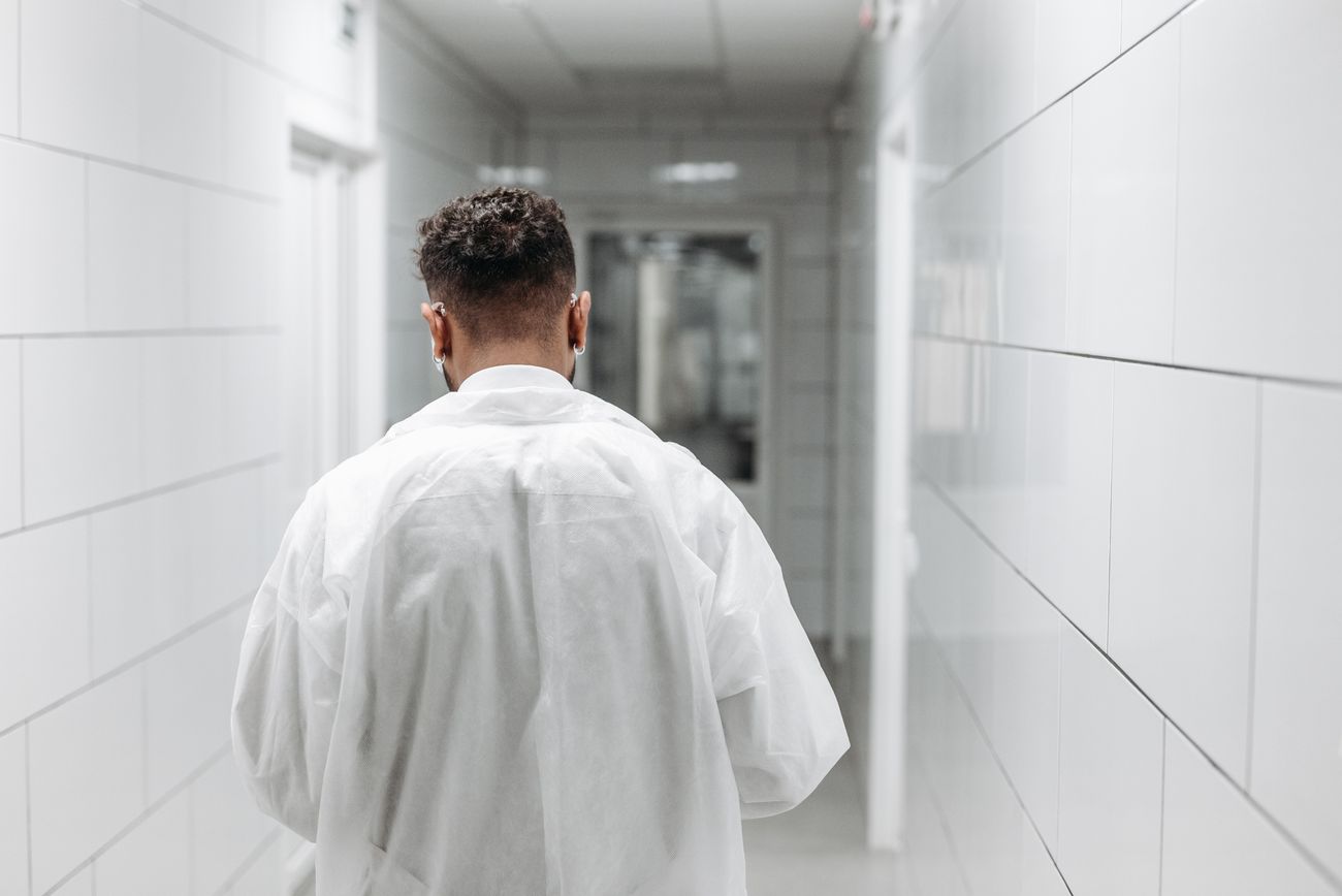 A member of staff in a white coat walking away down a hospital corridor