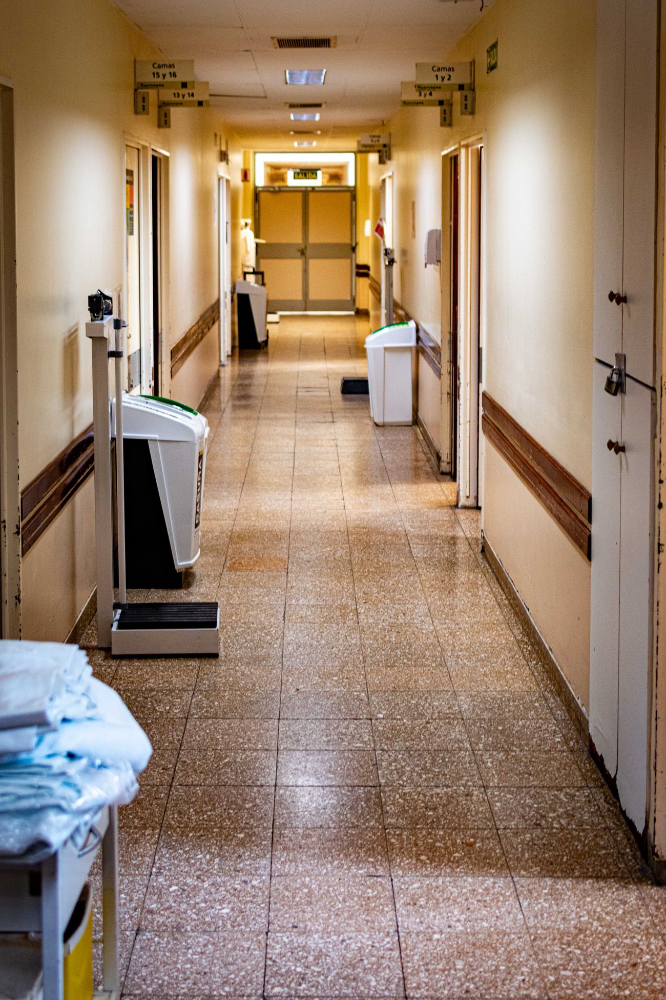A ward corridor with bins and a trolley parked by the exit doors